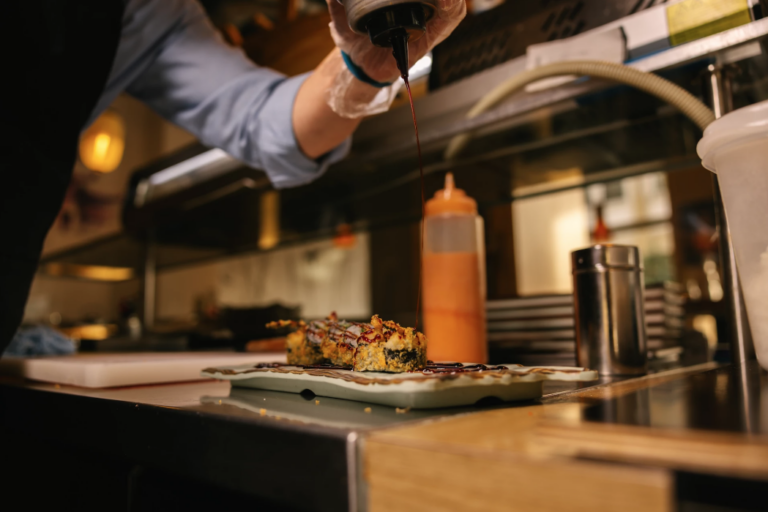 Sushirollen werden mit Soße dekoriert.